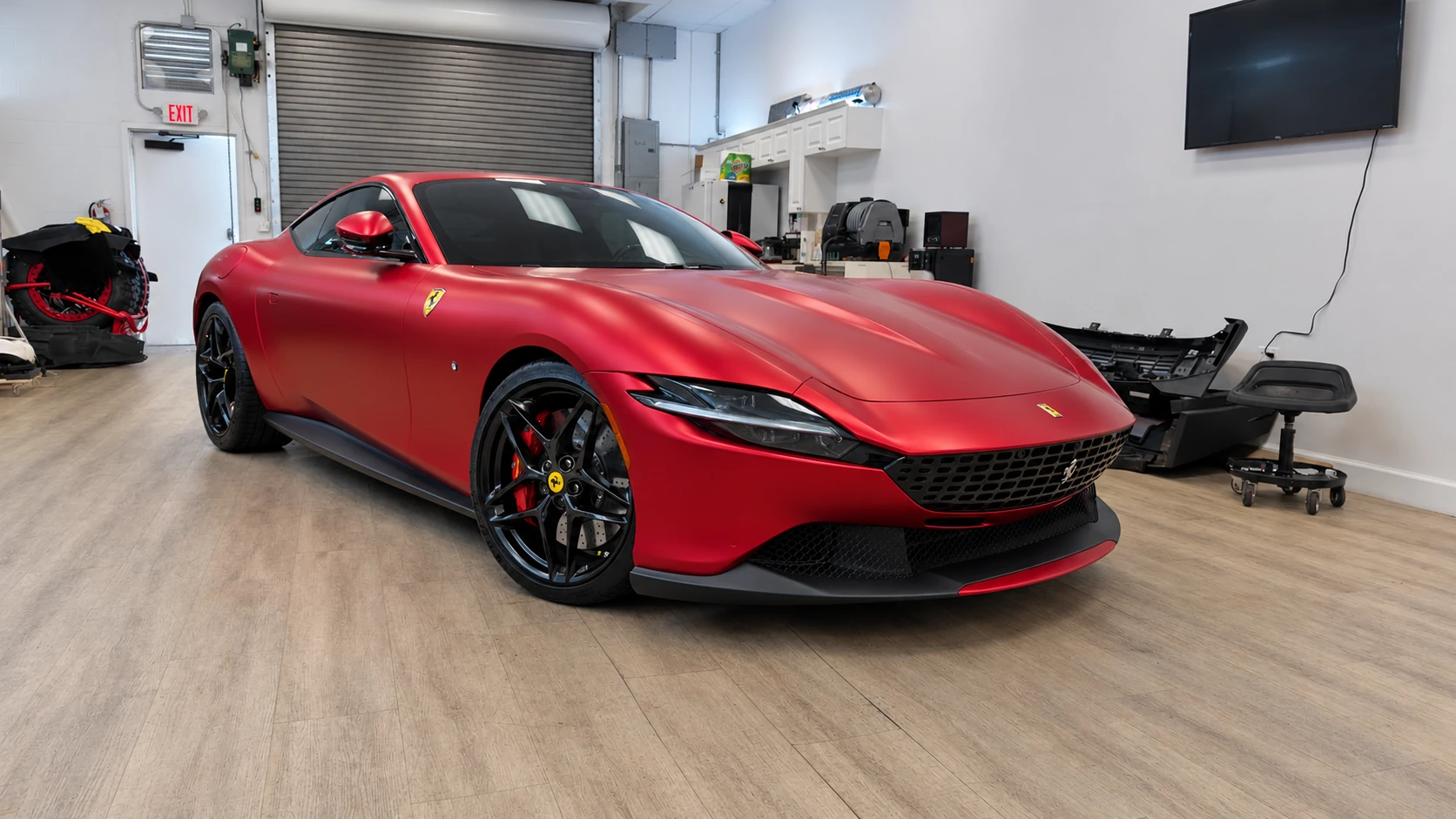 Ferrari Roma in matte red paint protection film with black wheels, front three-quarter view at Signature Customs in Oakland Park.